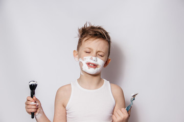 Portrait of a guy in shaving cream holding a razor and brush