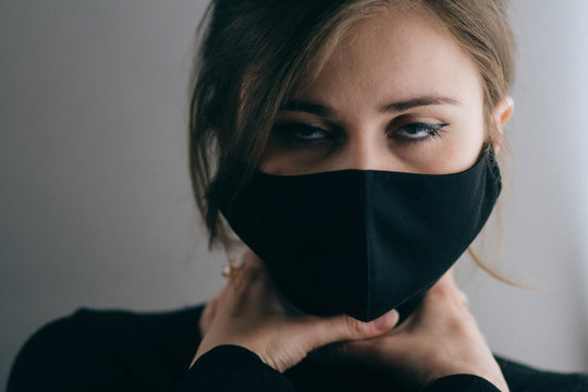 woman face in black protective mask with hands entwined around the neck, quarantine measures are strangling people and business, the epidemic is killing