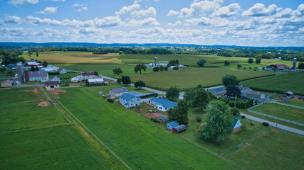 Fototapeta na wymiar Aerial view of Amish countryside with barns and silos and a one room school house on a sunny summer day