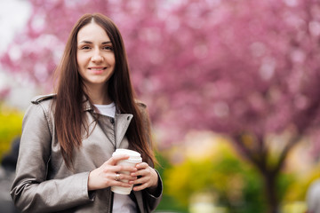Close-up portrait of a brunette girl on a background of Japanese cherry blossom tree.