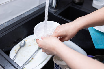 female hands wash dishes in the kitchen sink