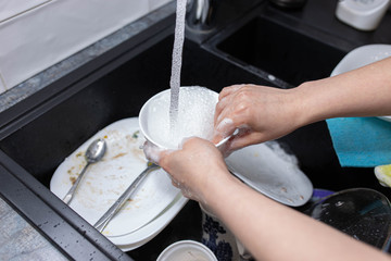 female hands wash dishes in the kitchen sink