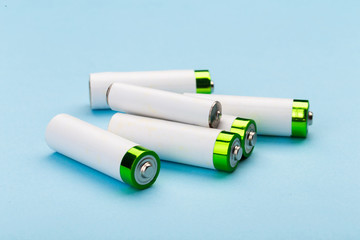 many new and used batteries of different shapes, AA, round batteries on a blue background.