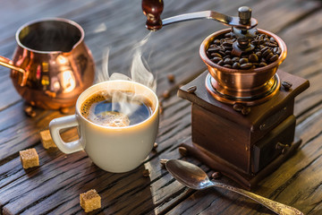 Coffee still-life. Hot cup of coffee and old-fashioned coffee grinder and cezve.