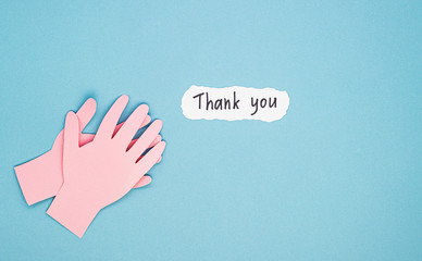 Fototapeta premium applauding paper hands and a thank you sign on a blue background