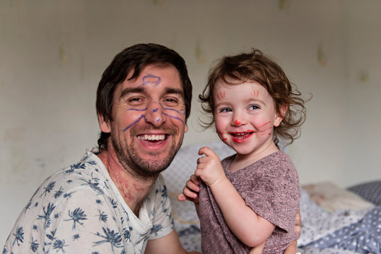 Dad plays with his daughter to isolate himself. Early childhood development. Dad and his daughter paint each other on their faces. Aqua at home. The entertainment is quarantined.