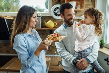 Happy family talking while having a healthy appetizer in the kitchen.
