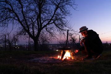 A man throws a firewood into the fire. Close up photo of bonfire in the backyard