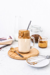 Trendy dalgona coffee in glass on white background.Korean drink latte espresso with foam of instant coffee. New popular food and drink trend. Selective focus