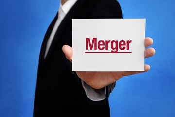 Merger. Lawyer in a suit holds card at the camera. The term Merger is in the sign. Concept for law, justice, judgement