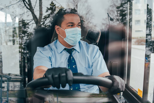 prevent the spread of coronavirus. young hispanic bus driver wearing a protective mask and looks at road.