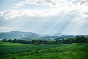 Fototapeta premium Rural landscape somewhere in Europe. Countryside farm, trees, green field, sunlight and cloud