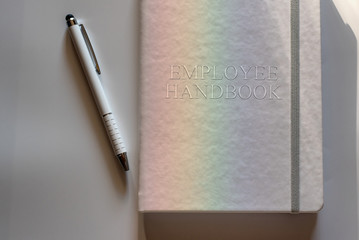 White Employee Handbook or manual with White pen on white surface lit by a light dispersed into...