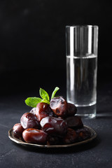 Ramadan Iftar food. Dates fruits and glass of water. Close up. Vertical format. Kareem.