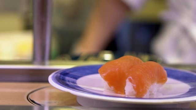 Slow motion of sushi on moving conveyor belt in a Japan restaurant. Traditional Kaitenzushi Japanese food. Shushi Go Round is a famous form of fast food common in Asia, also known as sushi train.-Dan