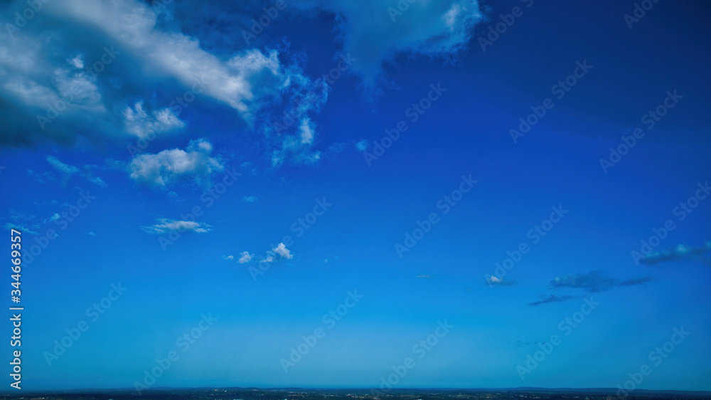 Wall mural blue sky and multiple clouds background showing a horizon