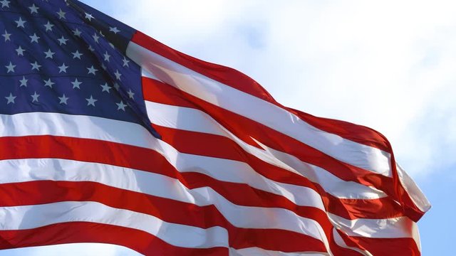 Closeup of large American flag waving in front of blue sky and white cloud. American Flag Waving. Close up of American flag waving. USA flag flaping in wind. American concept. CLOSE UP, 4K Video