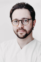 Obraz premium Portrait of handsome doctor brunet man in white coat in medical office with glasses. brutal and handsome man.