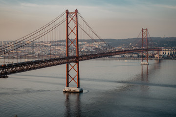 Fototapeta na wymiar '25 of April' Bridge over tagus river at sunset in Lisbon, Portugal. View from Sanctuary of Christ the King 'Cristo Rei'