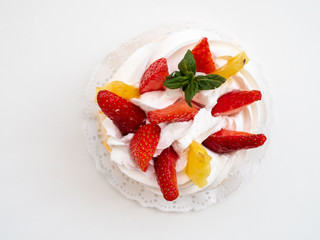 Close-up shot of creamy cake with fruits on white background. Space for text