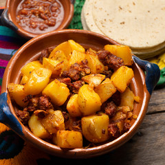 Mexican potatoes with chorizo on wooden background