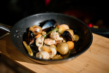 grilled seafood on frying pan in dark restaurant. shrimps and musselы