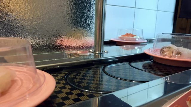 4K, Sushi on moving conveyor belt in a Japan restaurant. Traditional Kaitenzushi Japanese food. Shushi Go Round is a famous form of fast food common in Asia, also known as sushi train.-Dan