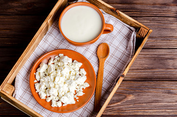 Homemade dairy products - kefir, cottage cheese in a wooden tray on a wooden background.