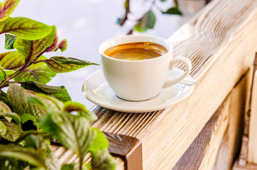 Cup of black aromatic coffee in a white cup on a wooden background.