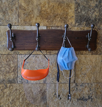 face mask or surgical chinstrap, an stethoscope and a plastic face protector hanging