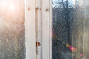 Old wooden window frame in winter or early spring with sun rays