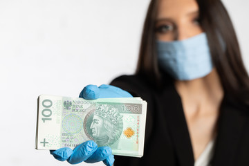 Businesswoman in a protective mask and protective gloves is holding a bundle of paper banknotes.