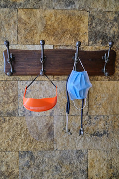 face mask or surgical chinstrap, an stethoscope and a plastic face protector hanging