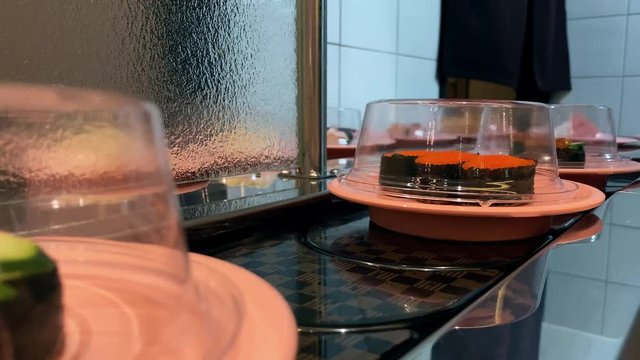 4K, Sushi on moving conveyor belt in a Japan restaurant. Traditional Kaitenzushi Japanese food. Shushi Go Round is a famous form of fast food common in Asia, also known as sushi train.-Dan