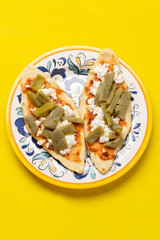 Mexican tlacoyos with nopal cactus and cheese on yellow background