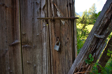 ein Riegel mit Vorhängeschloss am Tor einer verlassenen alten Scheune locked and lost
