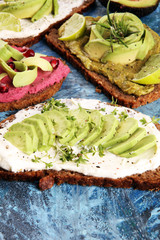 Avocado sandwich. Variation of healthy rye breakfast sandwiches with avocado and toppings like tomato and pomegranate