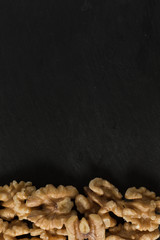 Walnut in wooden bowl on black background with copy space.Top view. Wooden plate with walnut on black background. Space for text