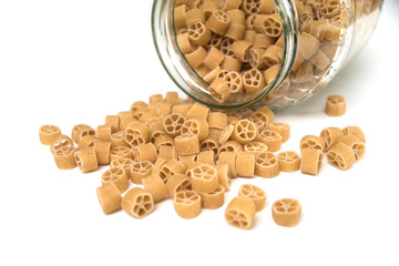  Closeup of gluten free pasta in shaped wheel falling from a glass container on white background