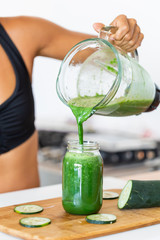 Latin woman staying healthy at home having a green juice