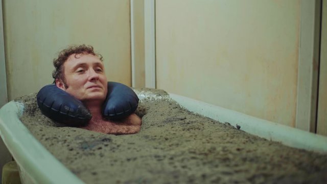 Man lies in a therapeutic mud bath,relaxation,