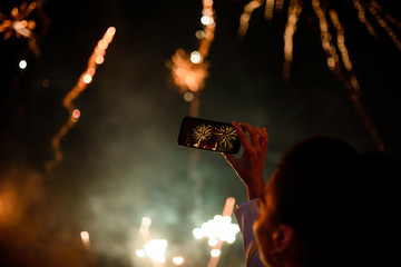 Hand of woman taking the photo to fireworks with the new smartphone.