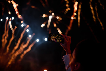 Naklejka na ściany i meble Hand of woman taking the photo to fireworks with the new smartphone.