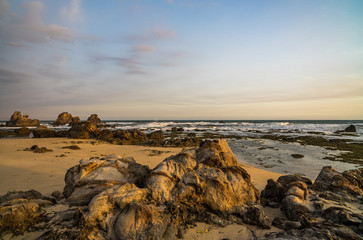 Nice lava rock formations at undiscovered beachlighted in golden evening glow found in Sawarna, Banten, Java, Indonesia
