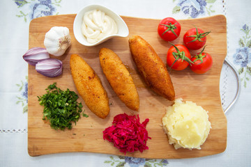 Ukrainian tradition food on a wooden board . Red cabbage sauerkraut in a small bowl . mashed potatoes . Mayonnaise, Garlic, Onion, Tomatoes. Chopped coriander.Chicken Kiev cutlets with parsley leaves.