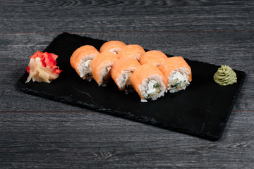 delicious sushi roll set on black plate in restaurant on gray table background