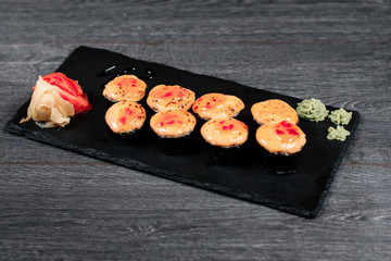 delicious sushi roll set on black plate in restaurant on gray table background