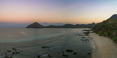 Wide scenic golden morning view of untouched beach, hills and RInjani volcano shot in Sumbawa island, NTB, Indonesia