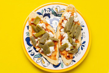 Mexican tlacoyos with nopal cactus and cheese on yellow background