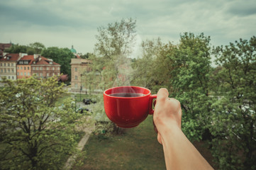 Obraz premium Holding a cup of coffee and in the background a landscape